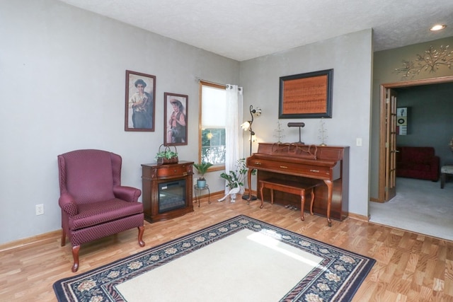 sitting room with a textured ceiling, baseboards, and wood finished floors