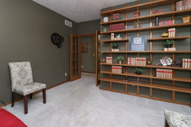 living area with baseboards, carpet, visible vents, and a textured ceiling