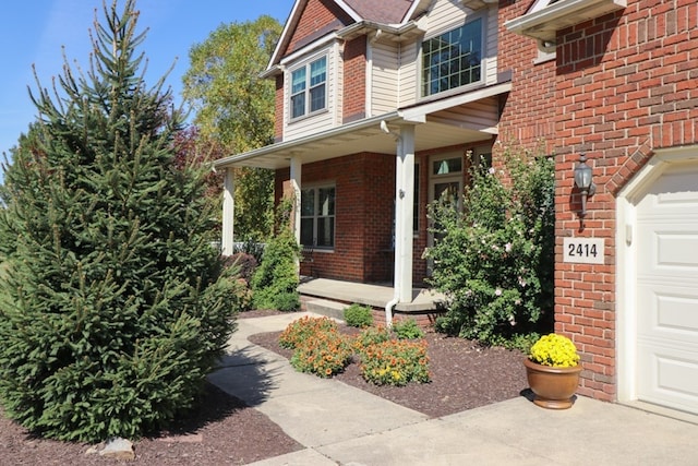 entrance to property featuring a porch and brick siding