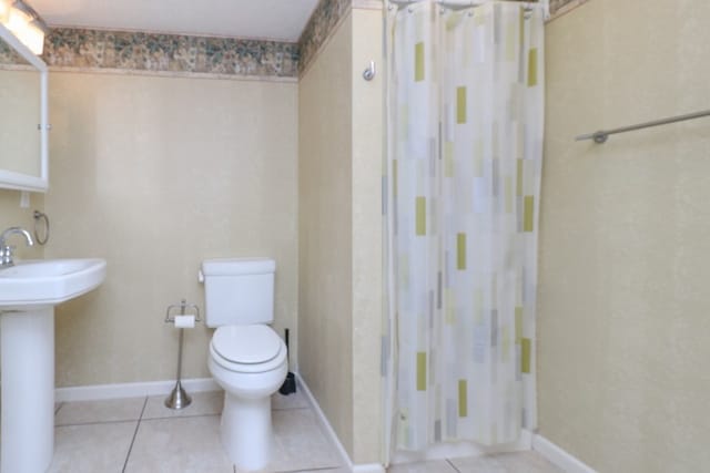 full bathroom with tile patterned flooring, a shower with curtain, baseboards, and toilet