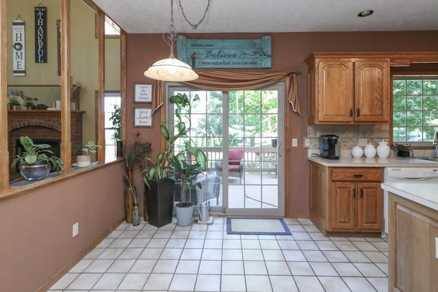 kitchen with light countertops, hanging light fixtures, brown cabinetry, and decorative backsplash