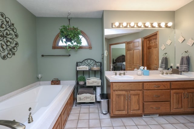 ensuite bathroom featuring a whirlpool tub, double vanity, a sink, and tile patterned floors