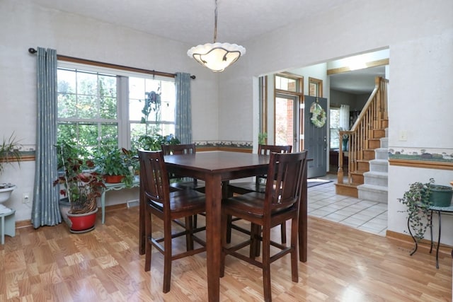 dining space with light wood finished floors and stairway