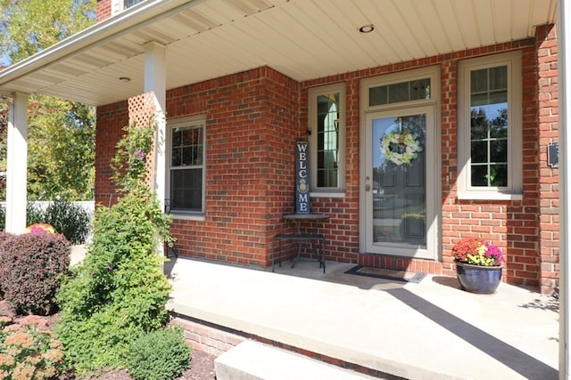 entrance to property featuring covered porch and brick siding