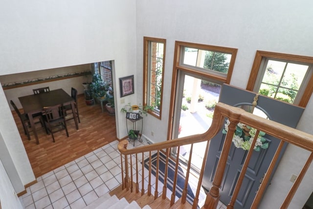 tiled foyer with stairs, a high ceiling, and baseboards