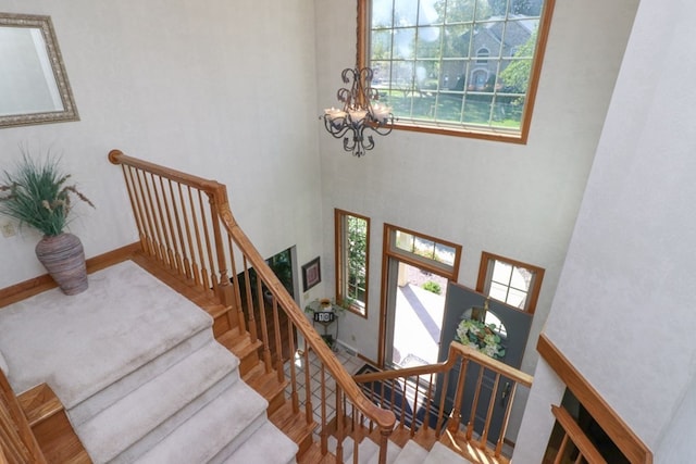 stairs with a chandelier, wood finished floors, and baseboards