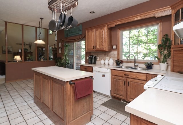 kitchen featuring brown cabinets, light tile patterned floors, a kitchen island, a sink, and dishwasher