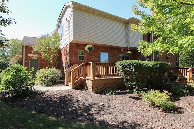 back of property featuring brick siding and a wooden deck