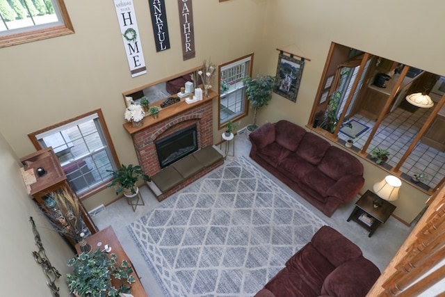 carpeted living room with a brick fireplace and visible vents