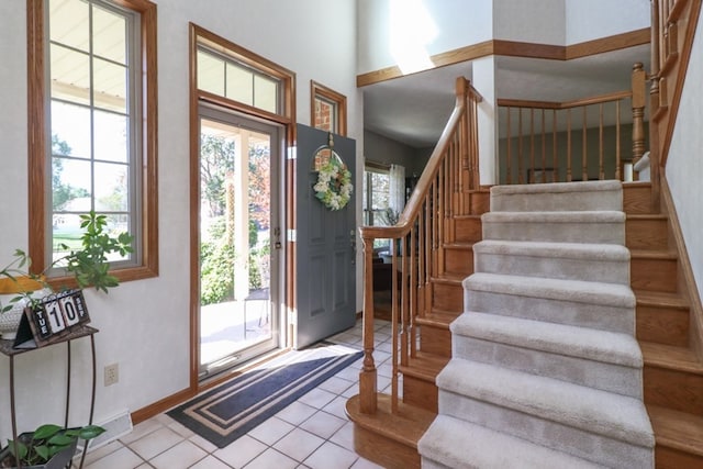 foyer entrance featuring stairway, light tile patterned flooring, and baseboards