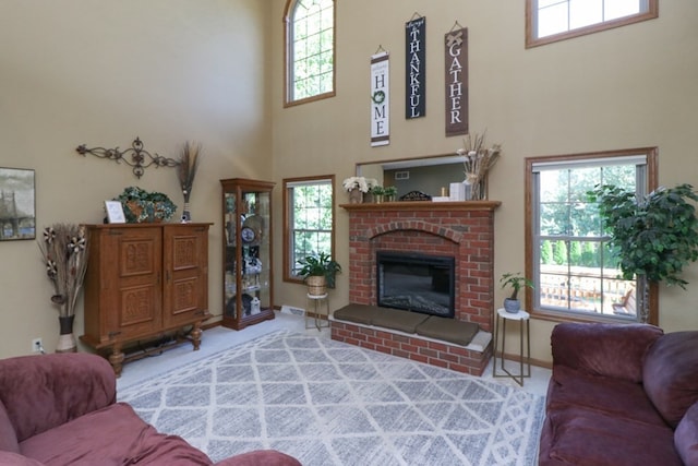 carpeted living area featuring baseboards, a high ceiling, plenty of natural light, and a brick fireplace