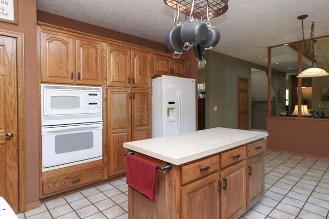 kitchen featuring light tile patterned floors, white appliances, a center island, brown cabinetry, and pendant lighting