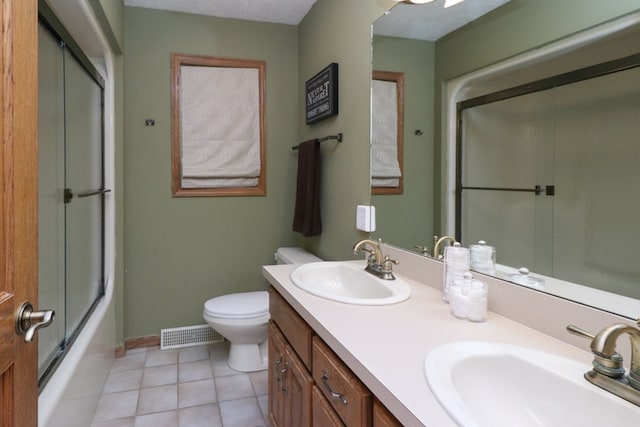 bathroom featuring toilet, double vanity, visible vents, and a sink