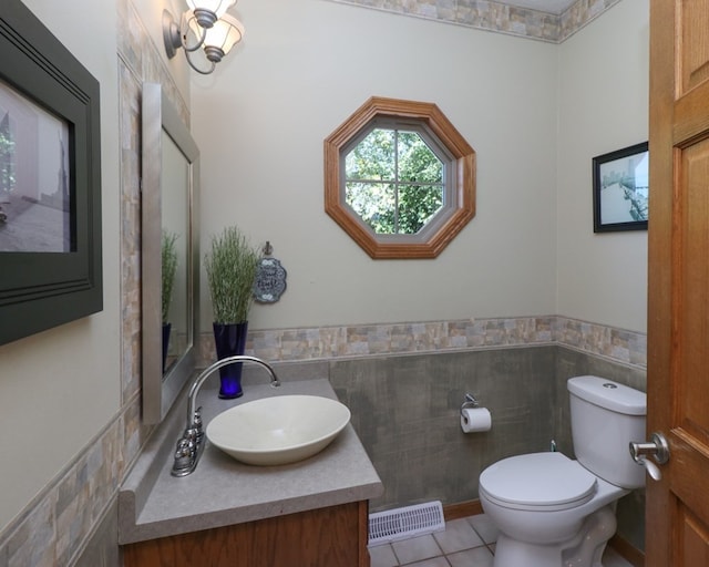 half bath featuring toilet, vanity, visible vents, wainscoting, and tile patterned floors