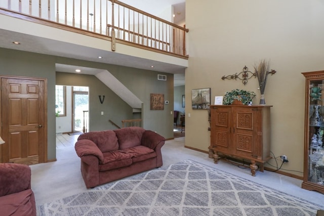 living room featuring visible vents, carpet flooring, a towering ceiling, and baseboards