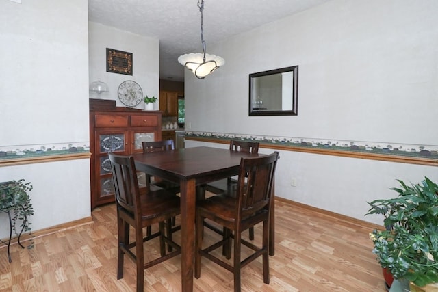 dining area with light wood-style flooring and a textured ceiling