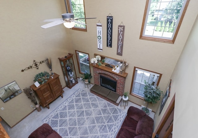 living room featuring ceiling fan, a fireplace, and a towering ceiling