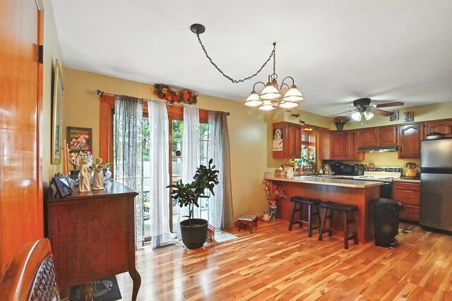 155 W Smiley Ave, Shelby, OH 44875 - kitchen with freestanding refrigerator, white electric stove, under cabinet range hood, light wood finished floors, and a peninsula
