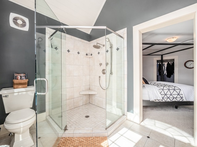 bathroom with tile patterned floors, toilet, and a shower with shower door