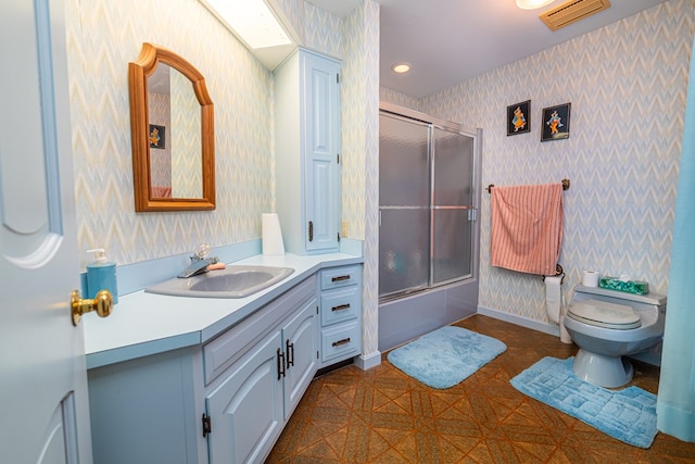 full bathroom featuring vanity, combined bath / shower with glass door, and toilet