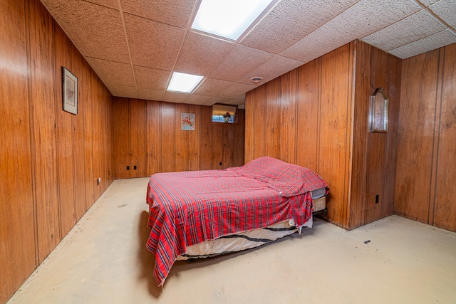 bedroom featuring a paneled ceiling and wood walls