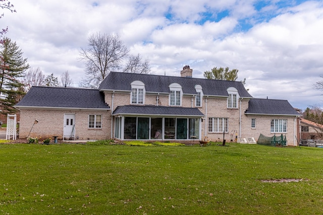 rear view of property featuring a yard and a sunroom