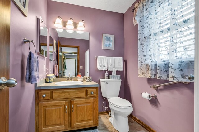 bathroom with baseboards, toilet, and vanity