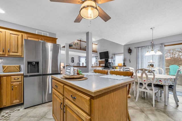 kitchen with a ceiling fan, stainless steel fridge, a center island, lofted ceiling, and visible vents