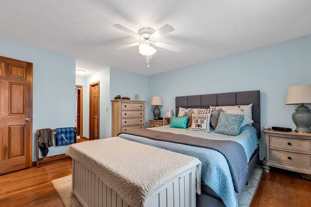 bedroom with a textured ceiling, ceiling fan, and wood finished floors