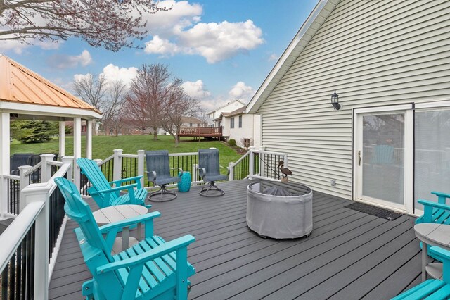 wooden deck featuring an outdoor fire pit and a yard