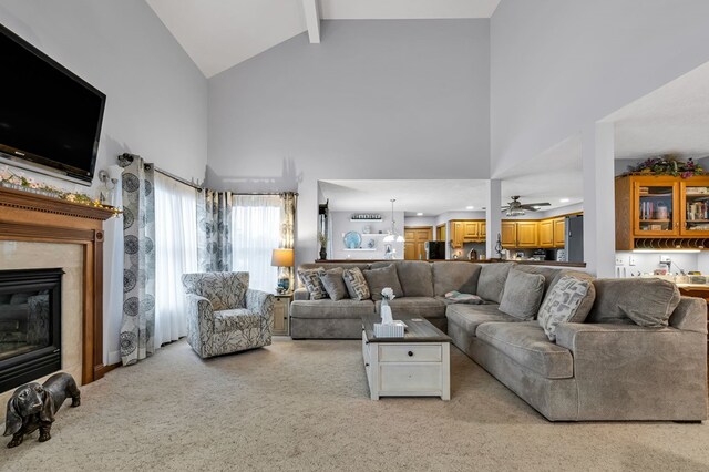 carpeted living room featuring a high end fireplace, a ceiling fan, high vaulted ceiling, and beam ceiling