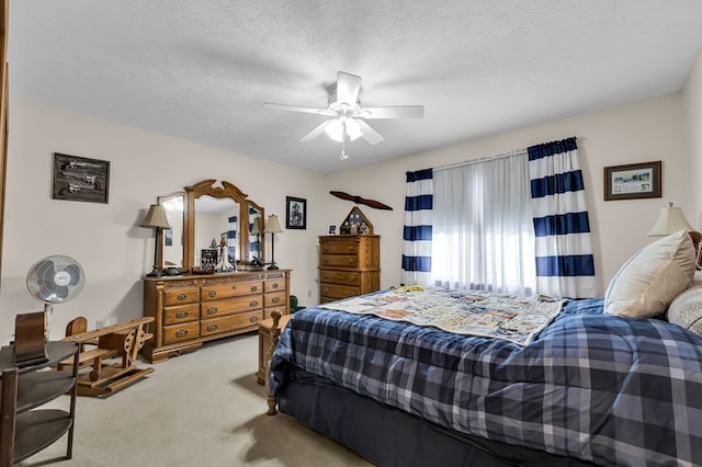 carpeted bedroom featuring a ceiling fan and a textured ceiling