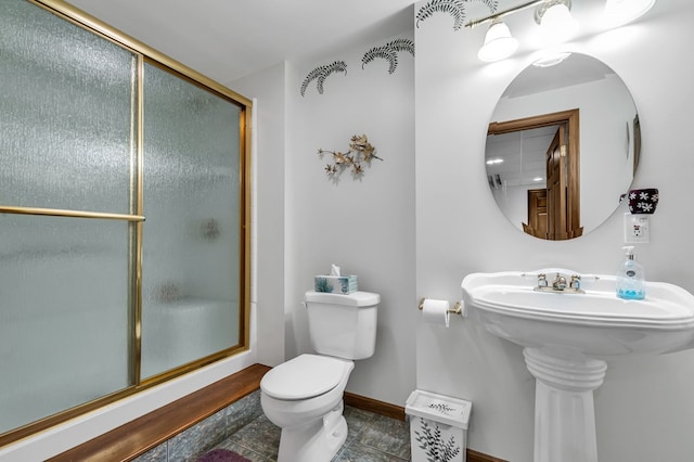 bathroom featuring a stall shower, tile patterned floors, toilet, a sink, and baseboards