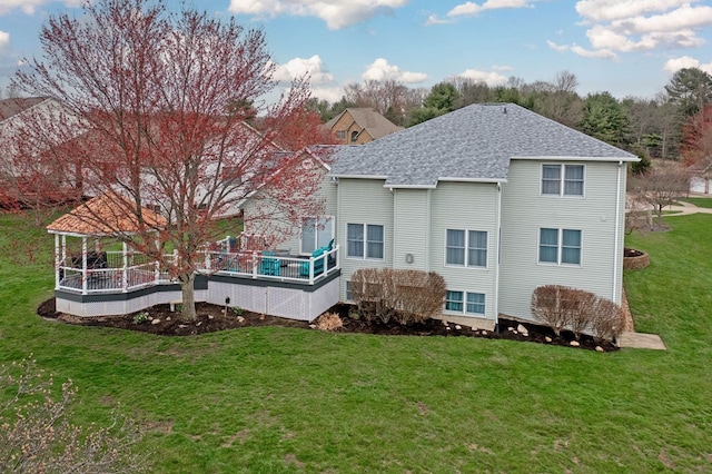 back of property with a lawn and a shingled roof