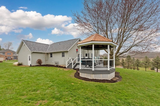 back of property with roof with shingles, a gazebo, a yard, and a deck