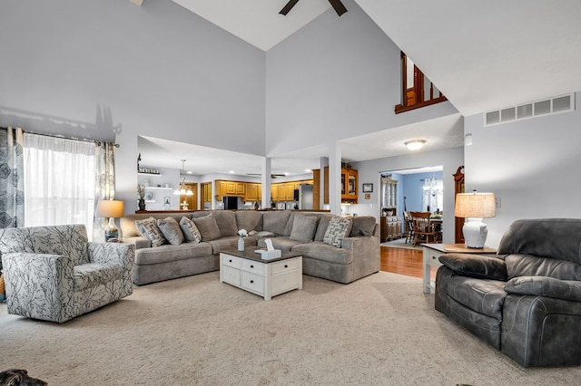 living area with a high ceiling, carpet flooring, ceiling fan, and visible vents