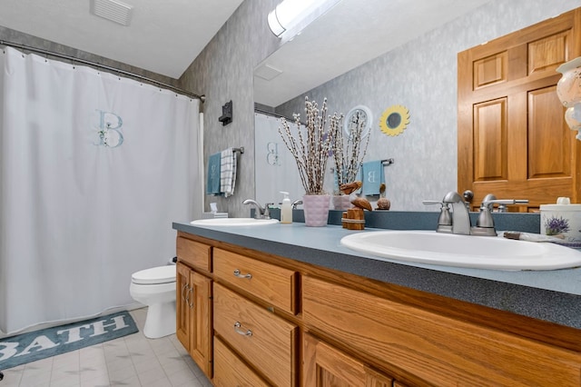full bath featuring double vanity, wallpapered walls, toilet, and a sink