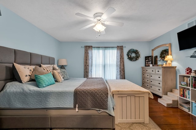 bedroom featuring a ceiling fan, wood finished floors, and a textured ceiling