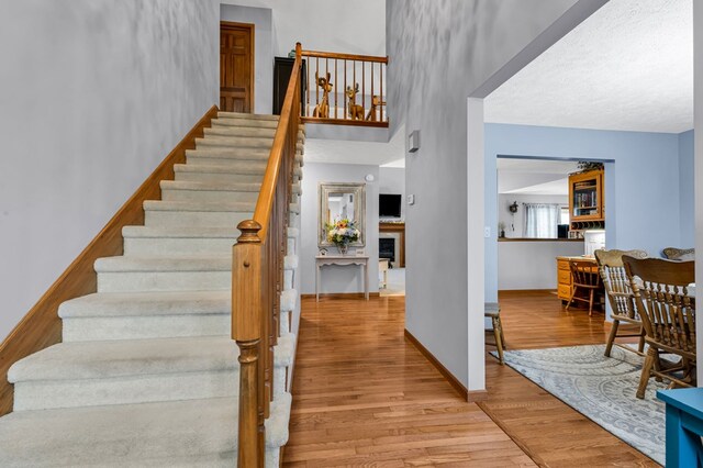 stairs with baseboards, a fireplace, and wood finished floors
