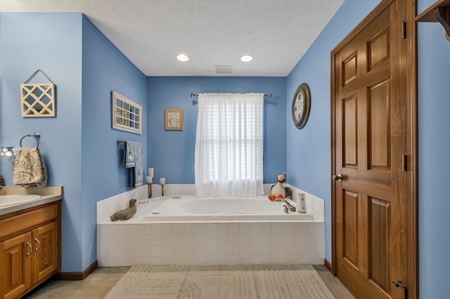 full bath with vanity, visible vents, a textured ceiling, and a bath