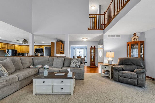 living room with light colored carpet, a high ceiling, baseboards, visible vents, and ceiling fan