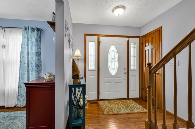 entryway featuring stairs, a textured ceiling, and wood finished floors