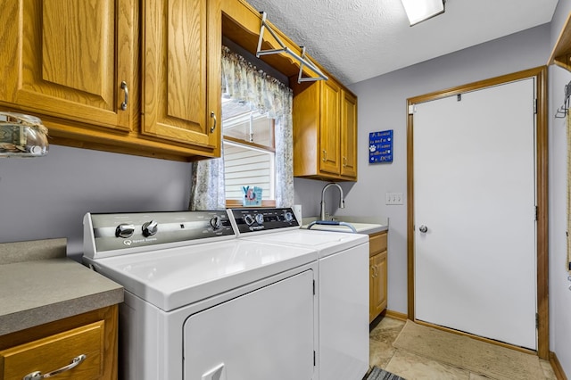 clothes washing area featuring a sink, cabinet space, washer and dryer, and a textured ceiling