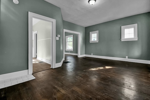 unfurnished room featuring wood-type flooring, baseboards, and a textured ceiling