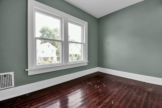 unfurnished room with dark wood-style flooring, visible vents, and baseboards