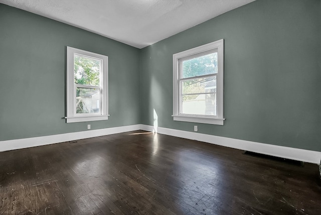 spare room featuring hardwood / wood-style flooring and baseboards