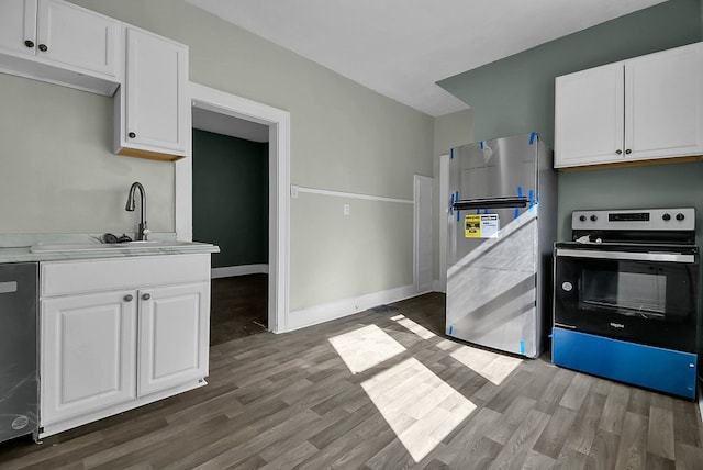 kitchen with appliances with stainless steel finishes, white cabinets, and wood finished floors