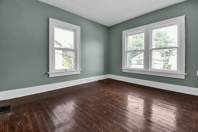 empty room with visible vents, baseboards, and hardwood / wood-style flooring