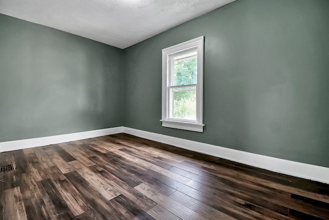 empty room featuring dark wood-type flooring and baseboards