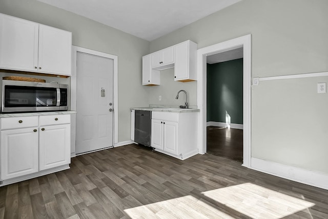 kitchen with light countertops, stainless steel microwave, white cabinetry, a sink, and dishwasher